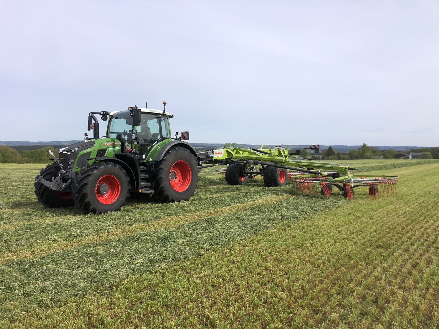 Tracteur Fendt Taserag avec andaineur Claas en action dans un champ