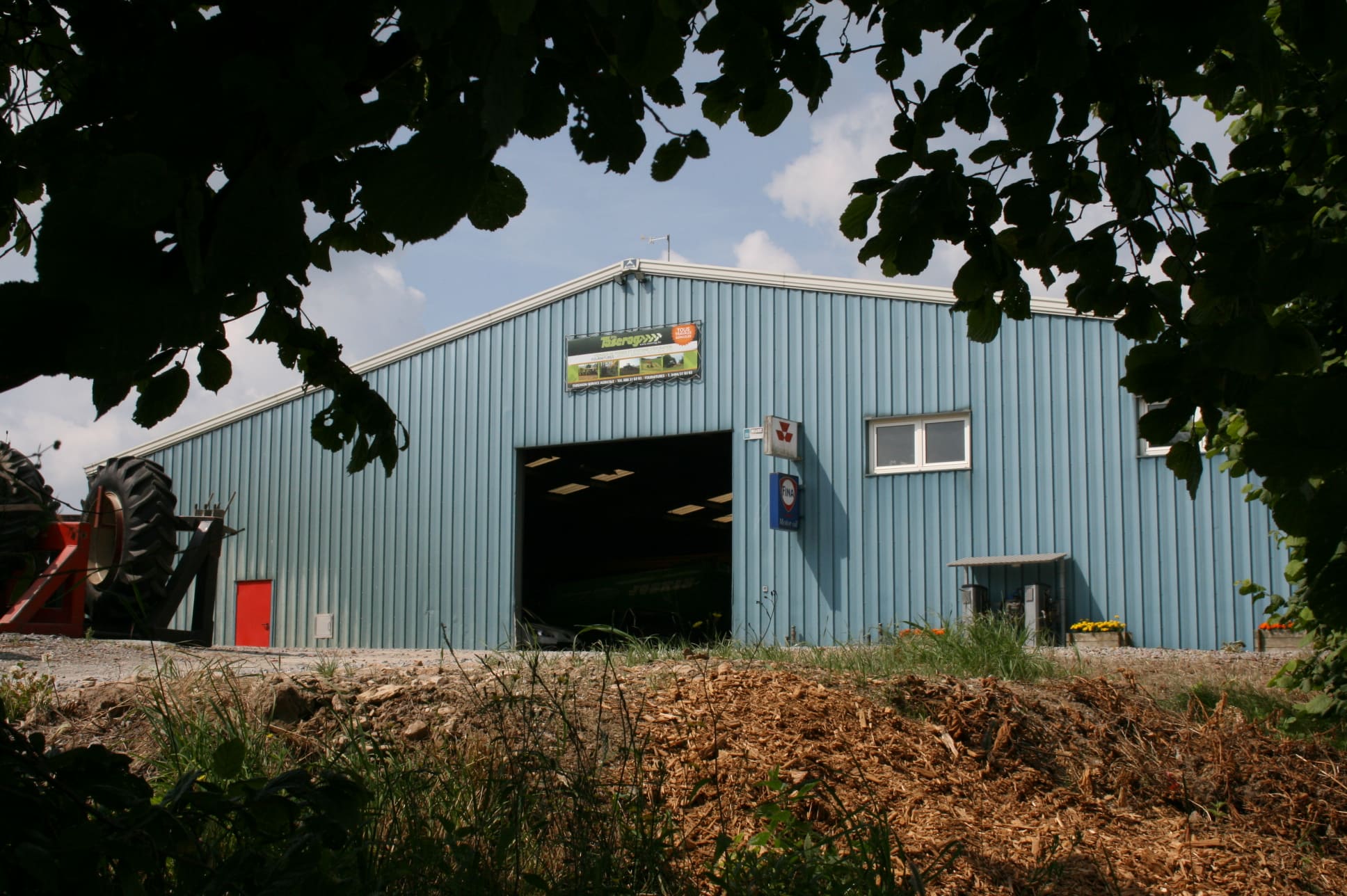 Hangar Taserag avec enseigne et matériel agricole à l'entrée