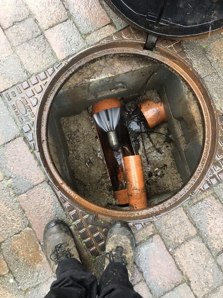 Technicien Taserag réalisant un hydrocurage de canalisation via un regard ouvert